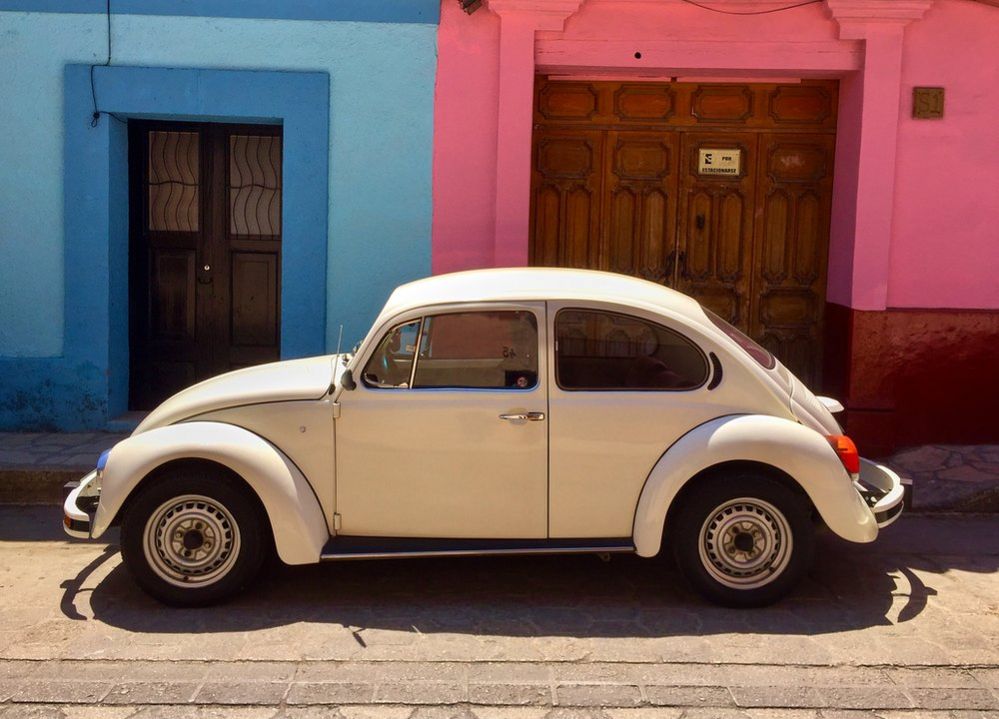 Volkswagen Beetle parked in front of a blue and pink building