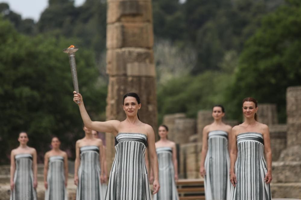 Greek actress Mary Mina (centre), in the role of the High Priestess, raises the torch of the Olympic Flame during the Olympic Flame lighting ceremony