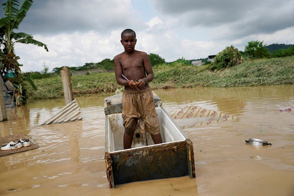 A boy stands on a floating refrigerator