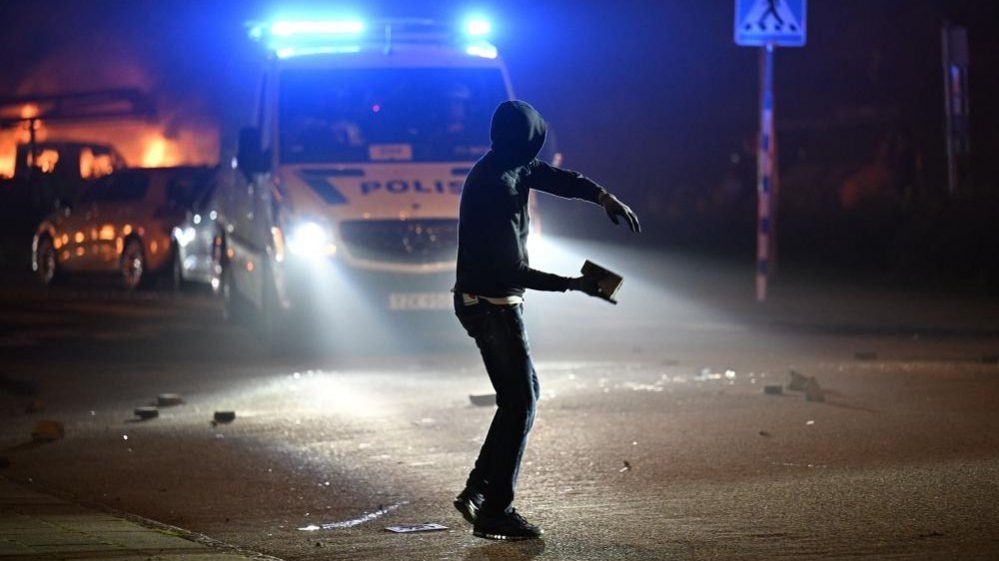 A protester throws a stone after a large number of cars were set on fire on Ramels vag in Rosengard