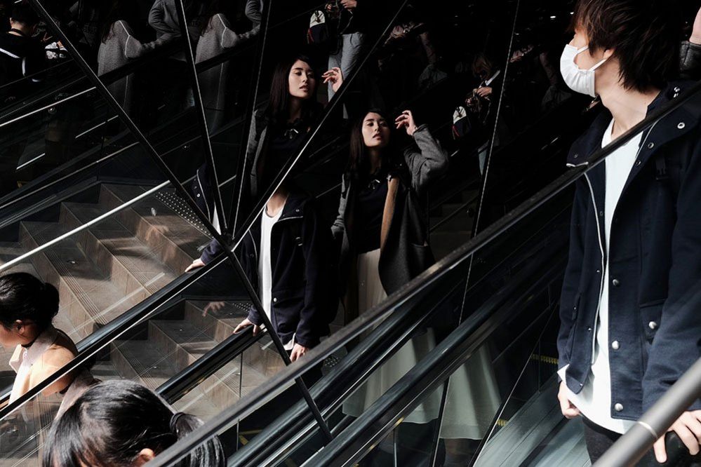 A woman catches her reflection as she descends the escalator