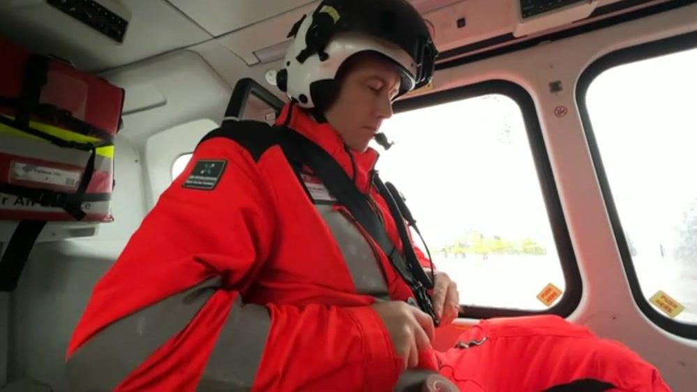 Specialist paramedic Ben Macauley in high-vis gear in a helicopter