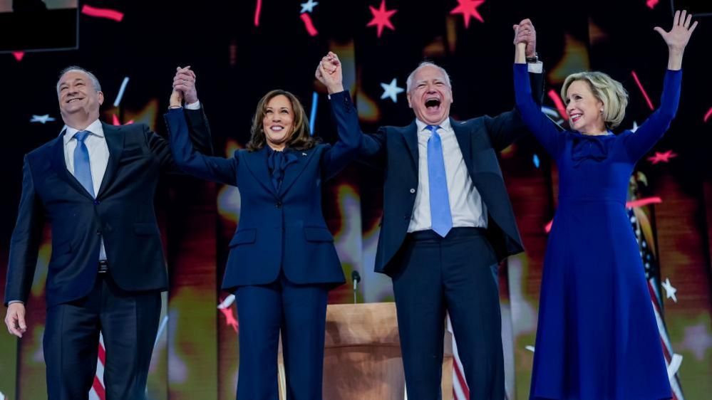 Doug Emhoff, Kamala Harris, Tim Walz and Gwen Walz hold hands at the Democratic National Convention