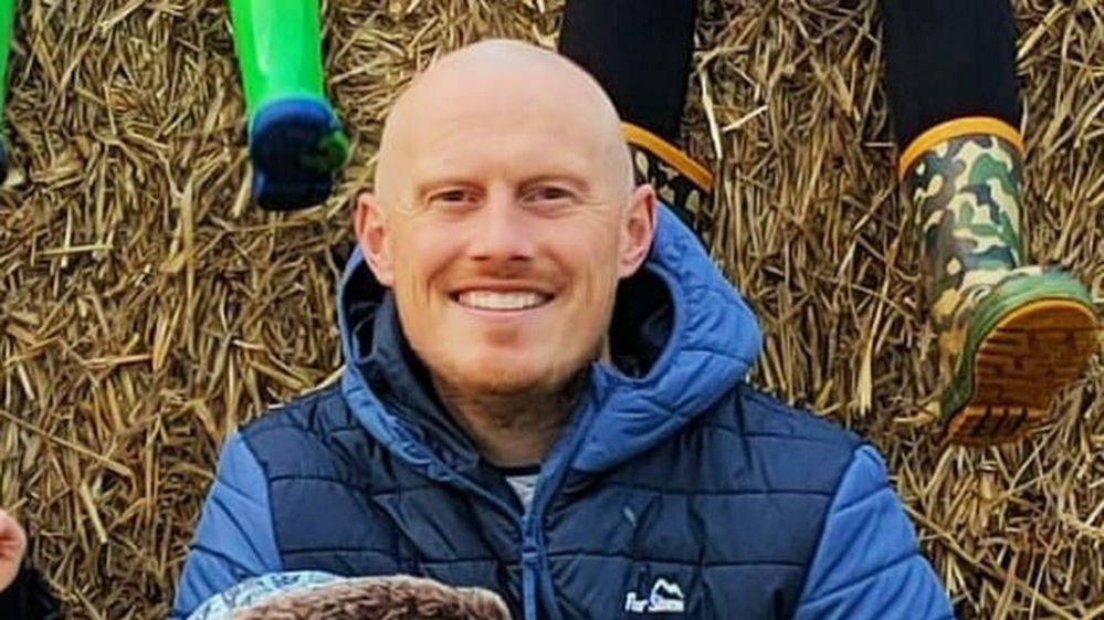 Close up of Martin McCarron in front of a hay bale smiling at the camera