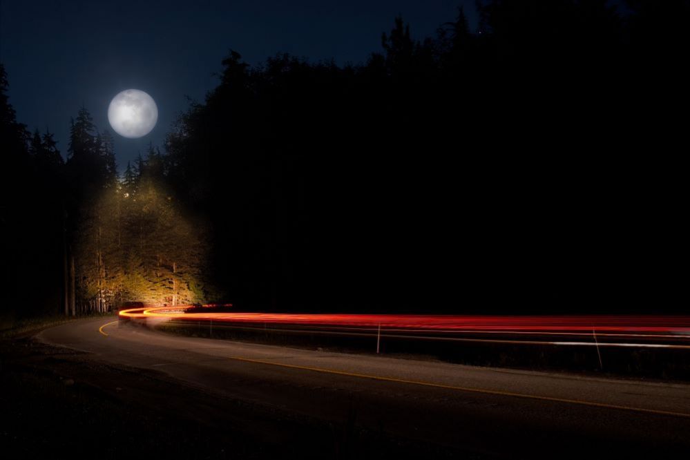 The moon over a road at night