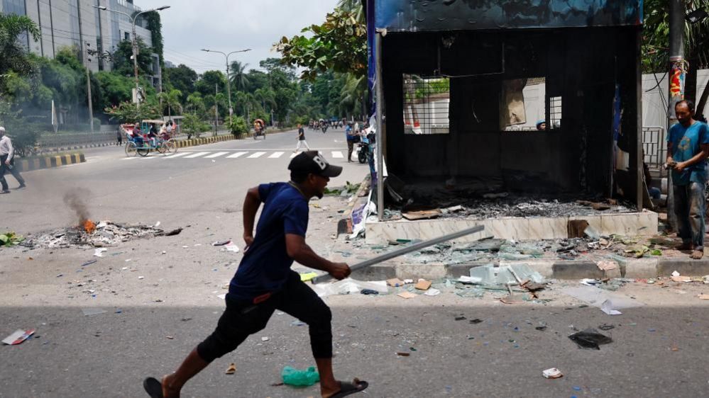 A demonstrator runs next to a vandalised police box during a protest demanding the stepping down of Bangladeshi Prime Minister Sheikh Hasina, following quota reform protests by students, in Dhaka, Bangladesh, August 4, 2024.