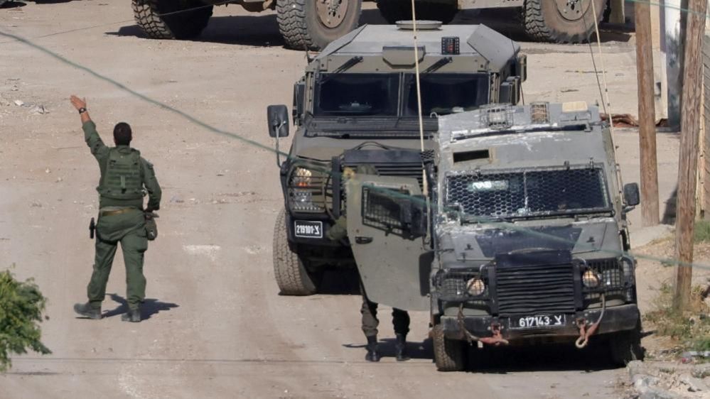 An Israeli soldier gestures as military vehicles operate in Jenin (04/09/24)