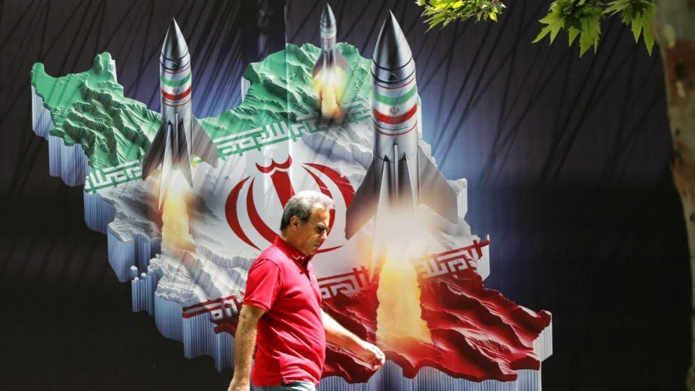 An Iranian man walks past a huge anti-Israeli banner carrying pictures of missiles on Iran's map, in Tehran (19/04/24)