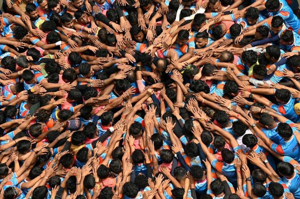 Hindu devotees pray before forming a human pyramid to break a dahi-handi (curd-pot) suspended in the air during celebrations for the 'Janmashtami' festival, which marks the birth of Hindu god lord Krishna, in Mumbai on August 19, 2022. (