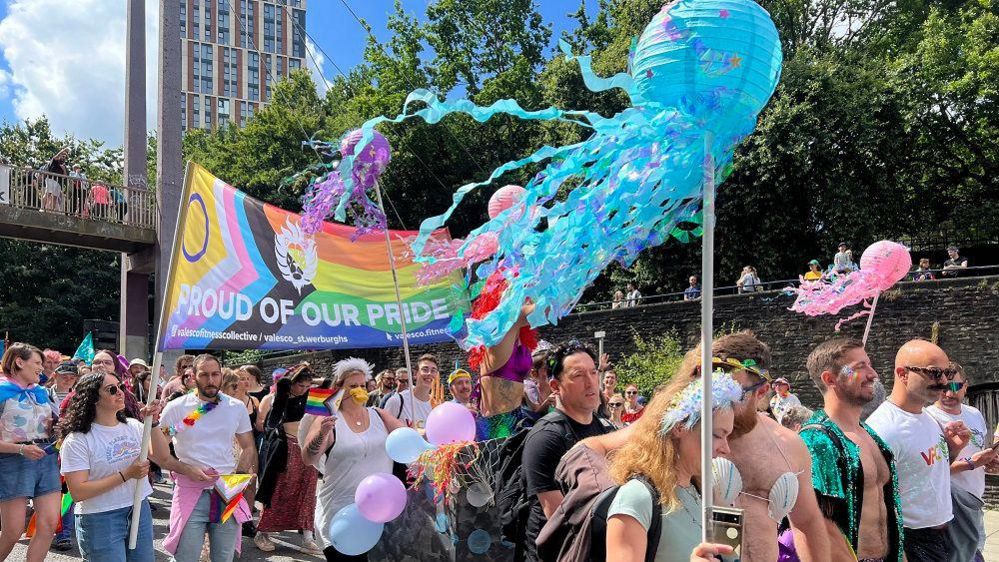 Crowd holding rainbow banner and streamers