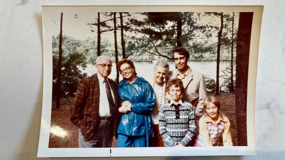 Four adults and two children standing in front of lake