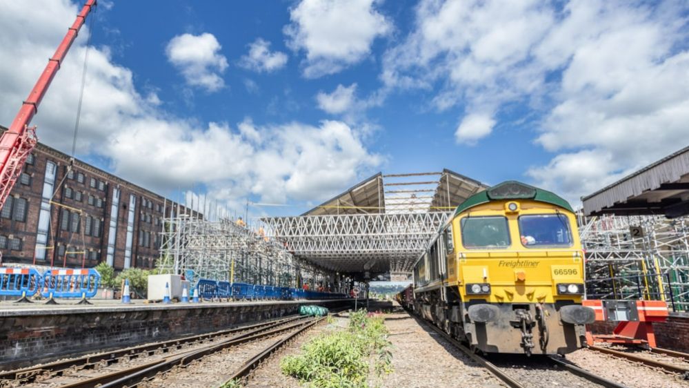 A yellow train sits on the rails outside Huddersfield railway station