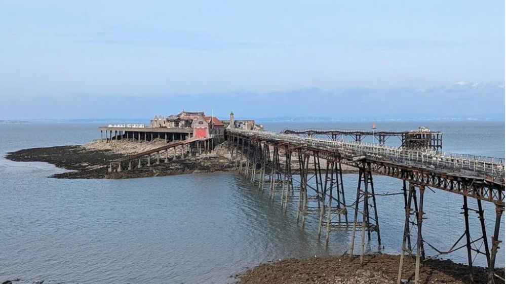 Birnbeck Pier seen slightly from the left - you can see the disrepair, with rusty metal and the fallen walkway in the distance 