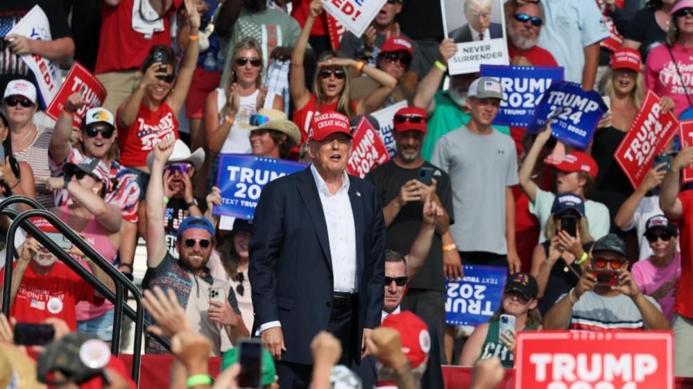 Donald Trump at a political rally with many ecstatic supporters behind him