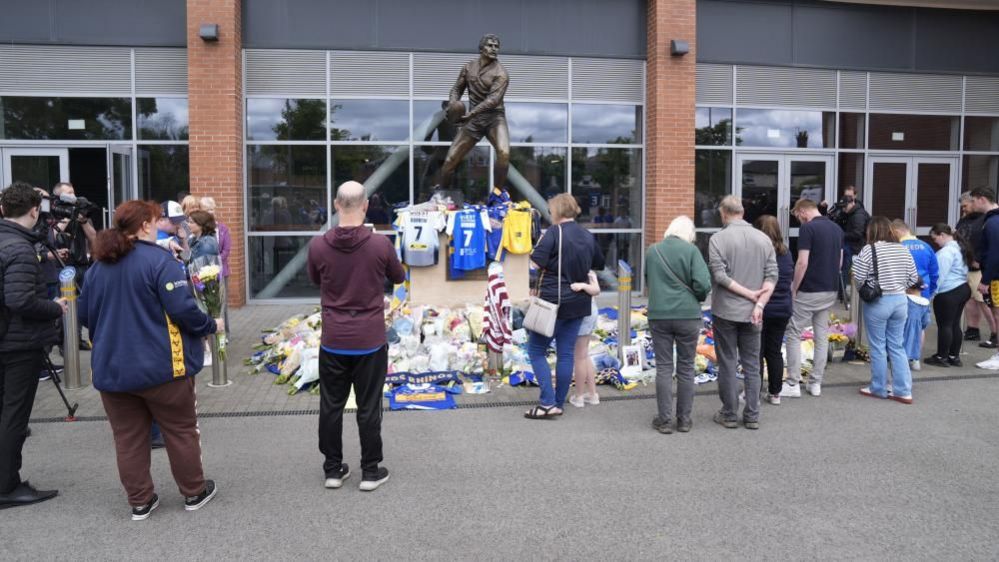 Members of the public pay tribute and view flowers and messages left at Headingley