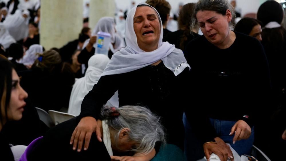 Two women mourn at funerals for children killed in a rocket attack at Majdal Shams on the Israeli occupied Golan Heights (28/07/24)