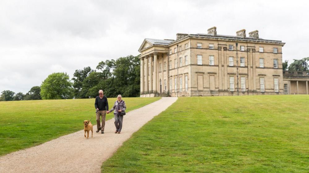 Dog walkers in front of a stately home