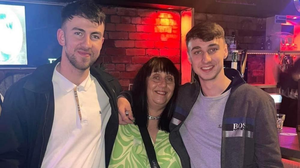 Zak Slater and Jay Slater stand either side of their mother, Debbie Duncan