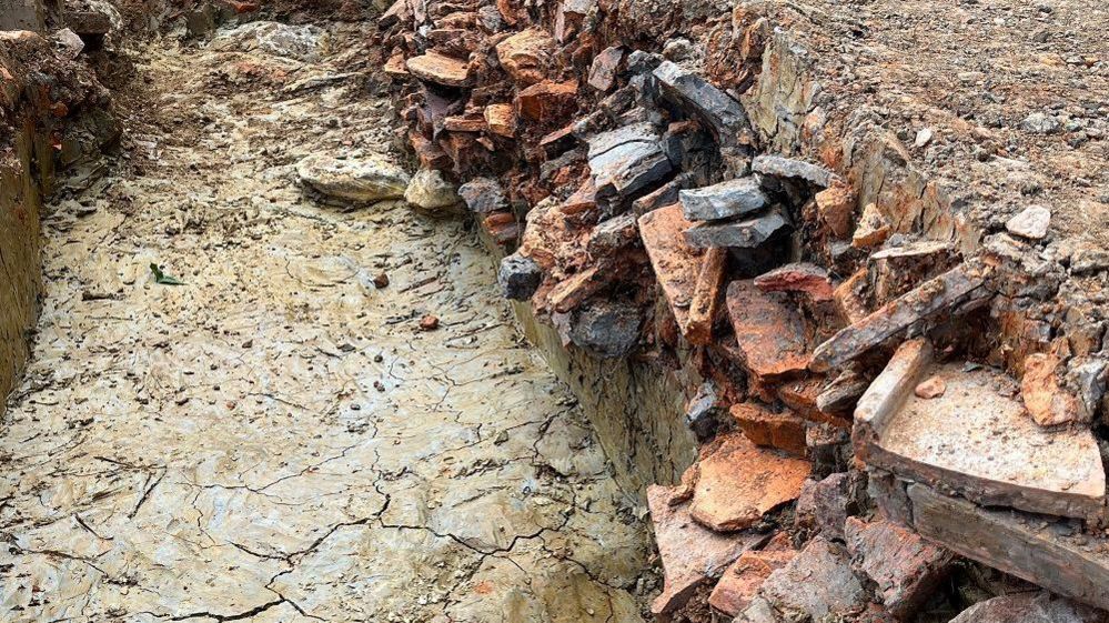 A trench-type hole with hundreds of broken tiles sticking out of the sides