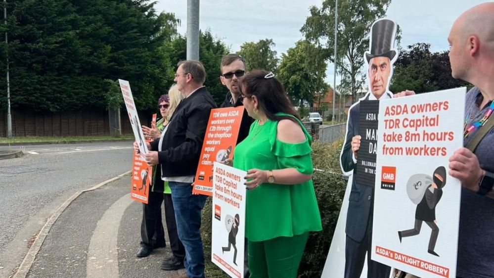 A line of men and women holding placards at the roadside