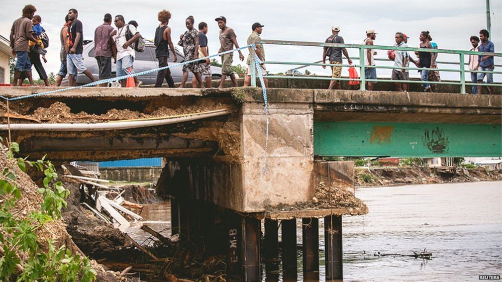 Pedestrians walk across a bridge damaged as a result of severe flooding near the capital Honiara in the Solomon Islands in this picture released by World Vision on 6 April, 2014