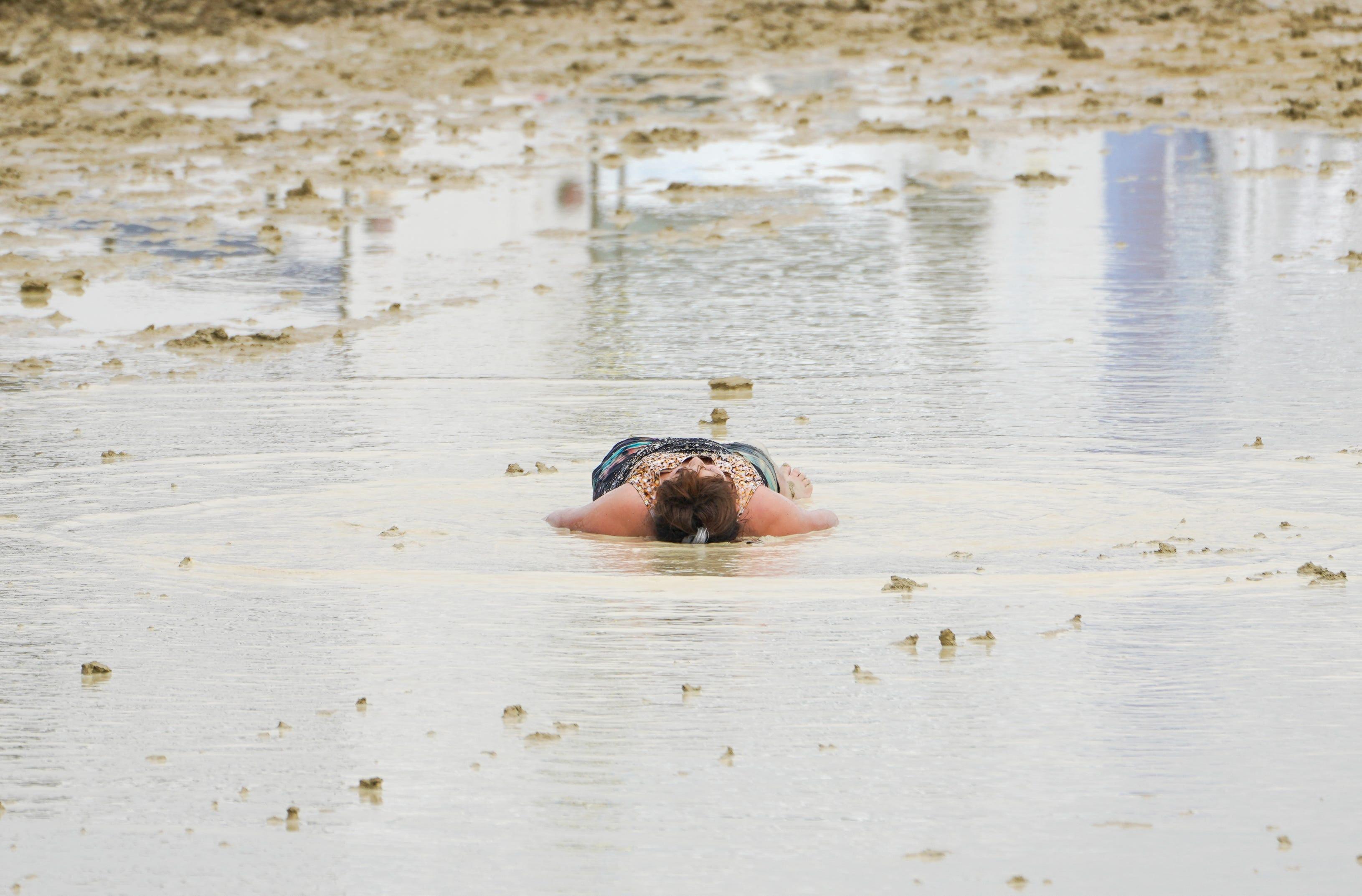 Una asistente de Burning Man tumbada en el barro y el agua durante el evento.