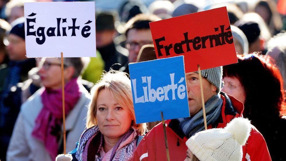 Personas con los carteles  "Egalite", "Liberte" y "Fraternite"