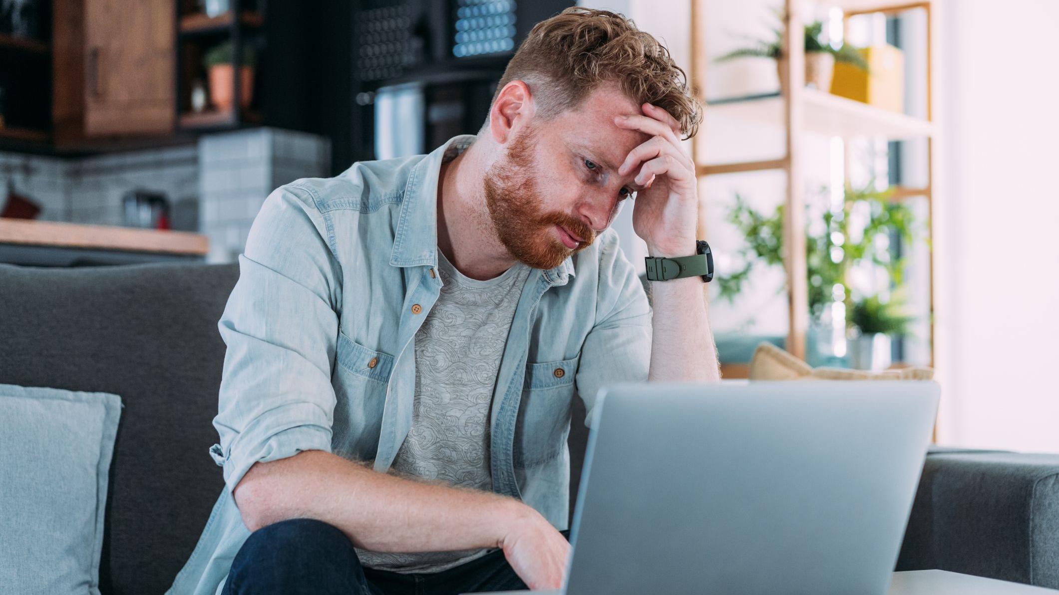 Homem olhando laptop em sofá