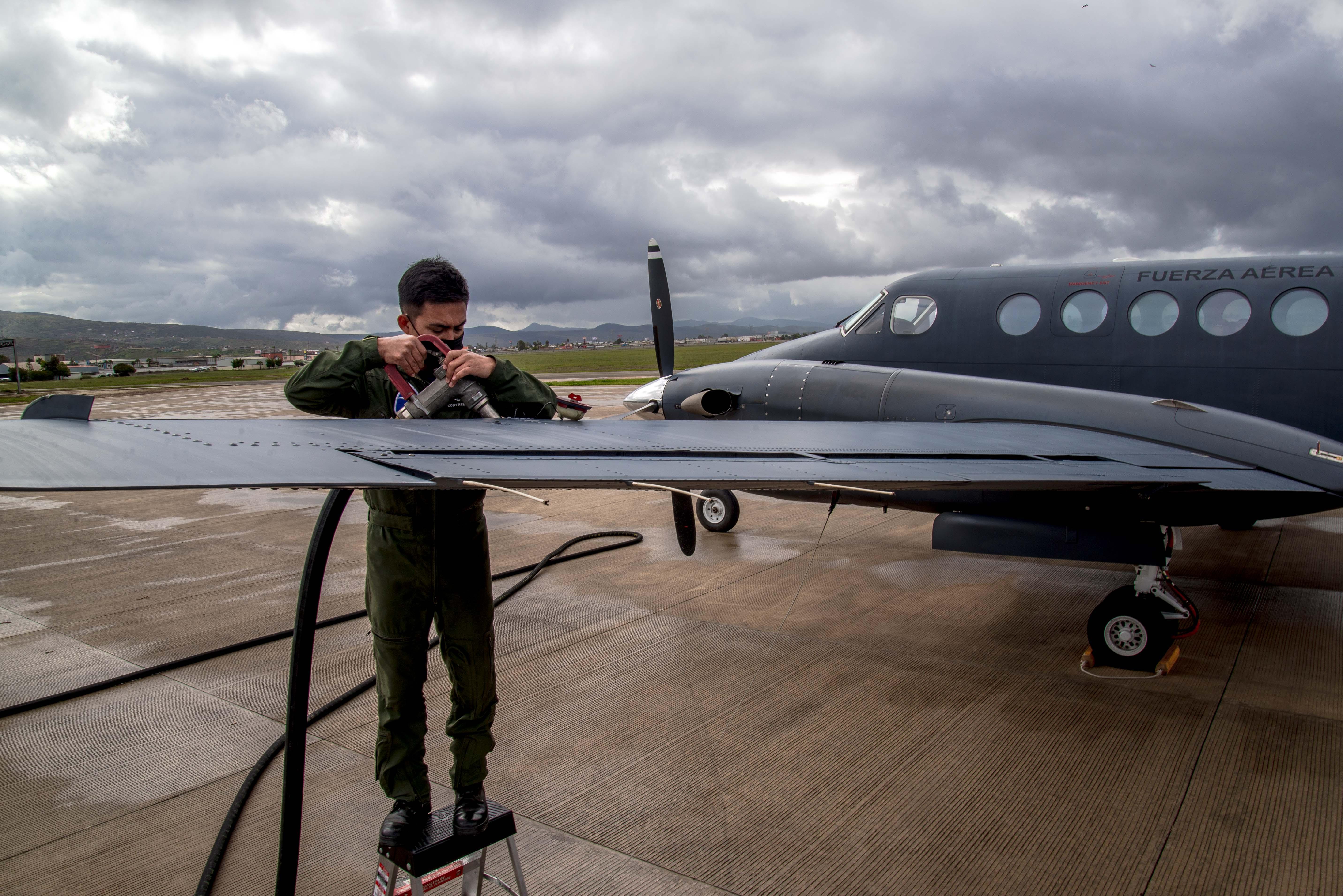 A pilot recharges fuel on the wing of an aircraft at FAM