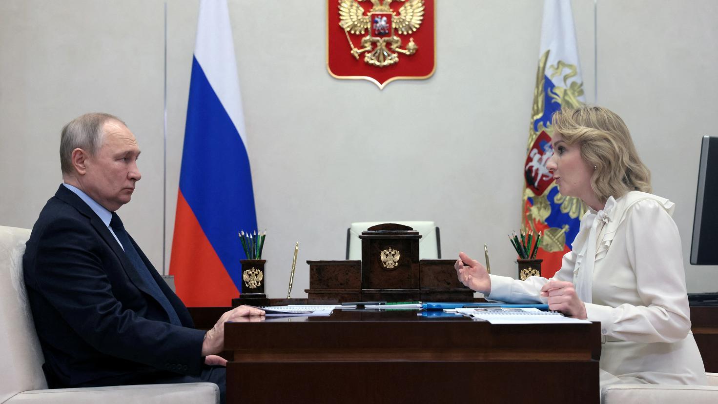 Putin e Belova frente a frente em reunião, com mesa os separando