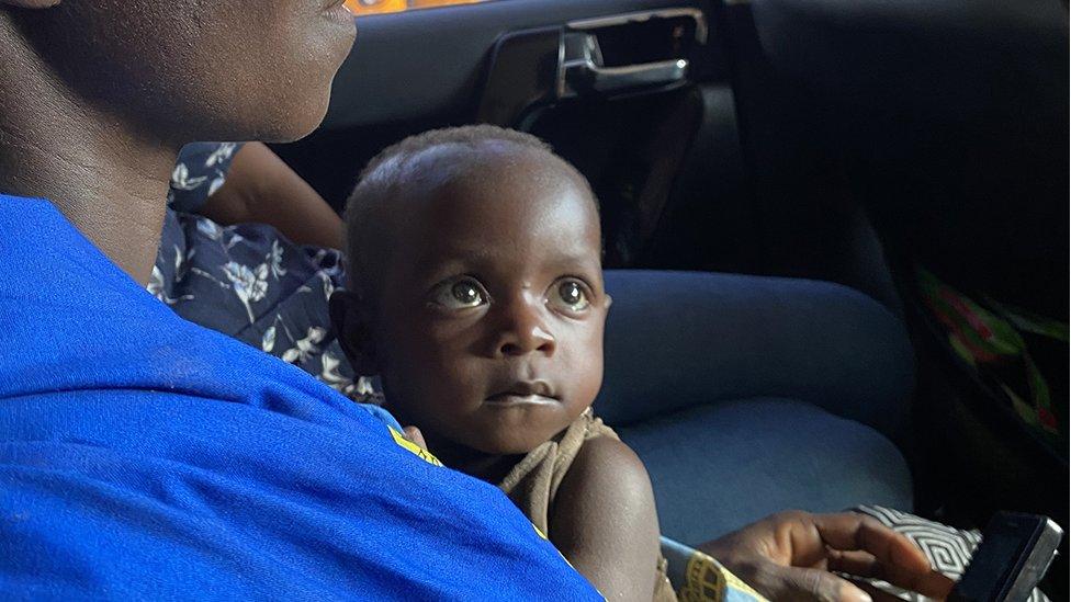 Mãe segurando bebê enquanto viaja de carro no Quênia