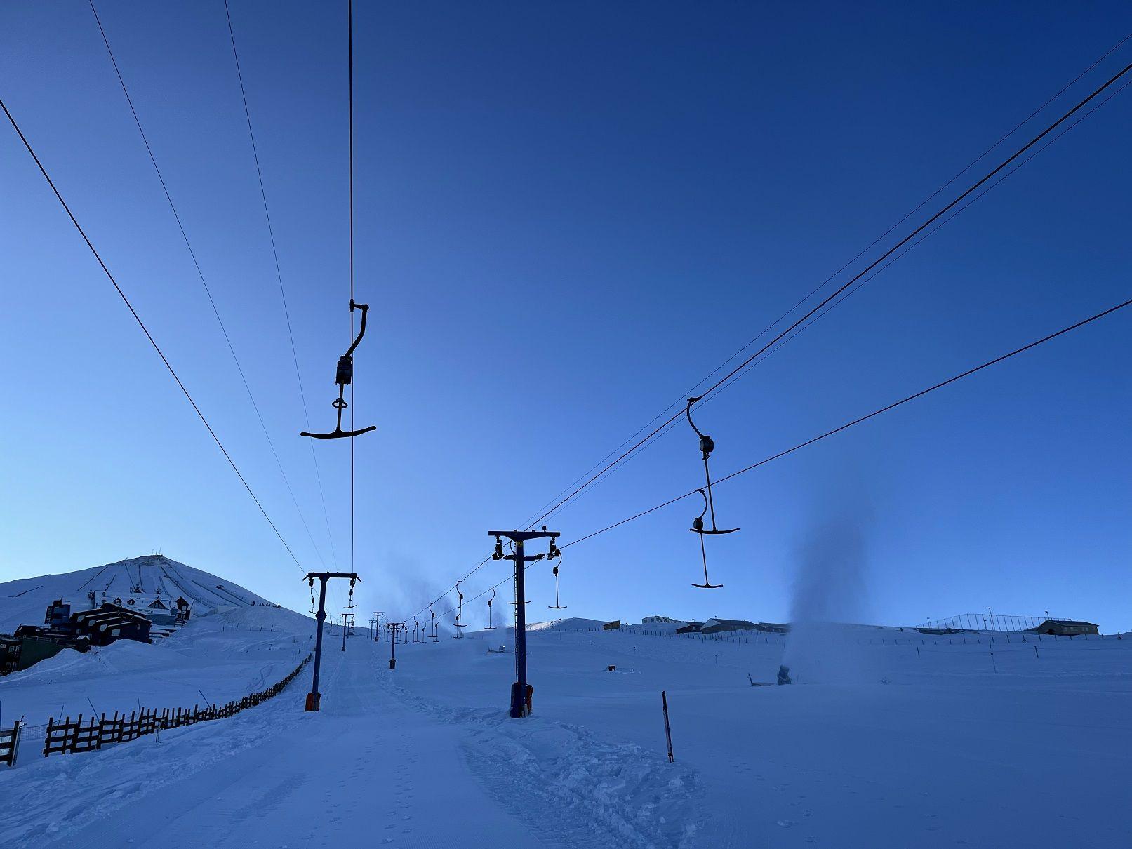 Teleférico em estação de esqui, com ‘fumaça’ de canhões de neve