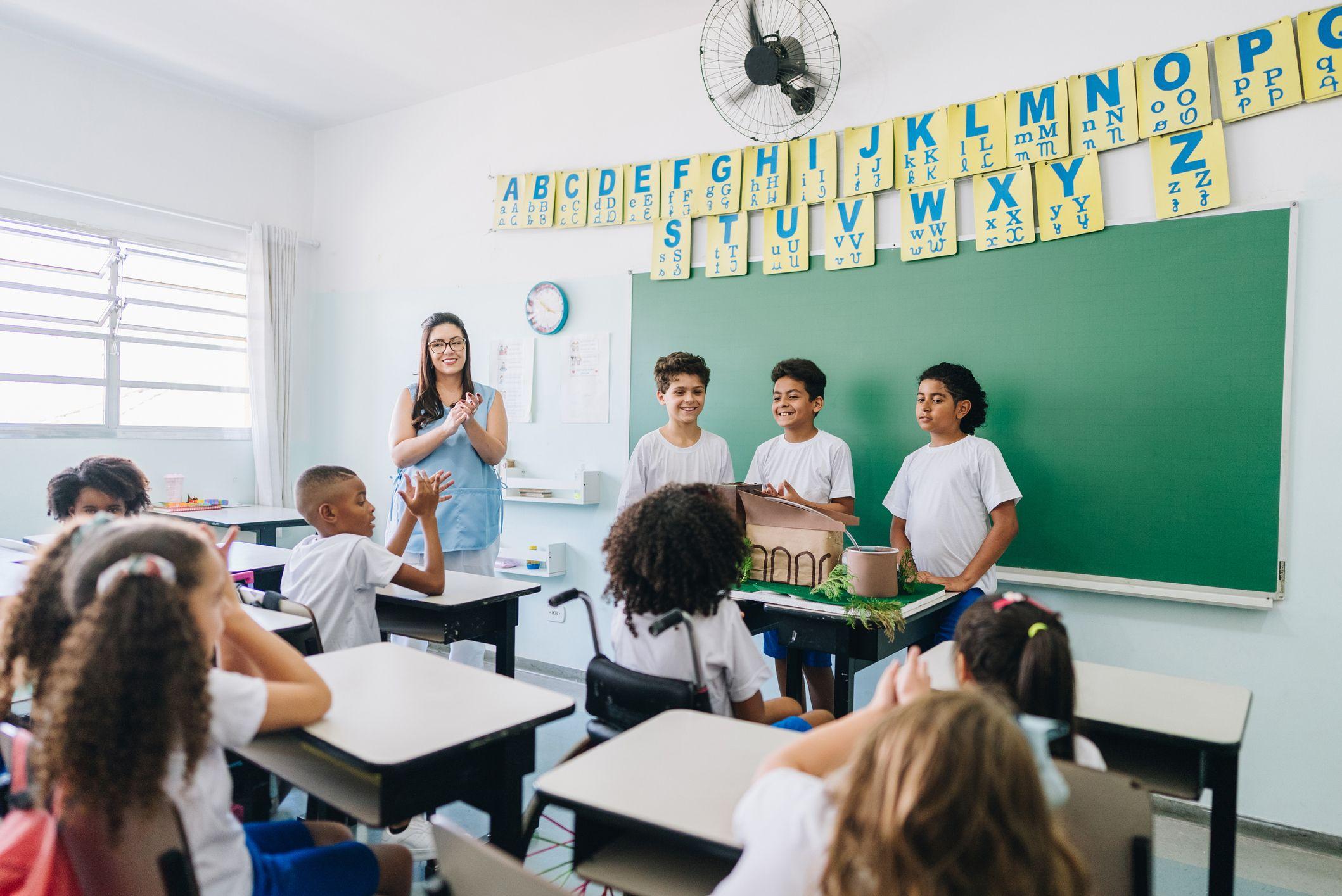 Niños en un aula aplaudiendo.