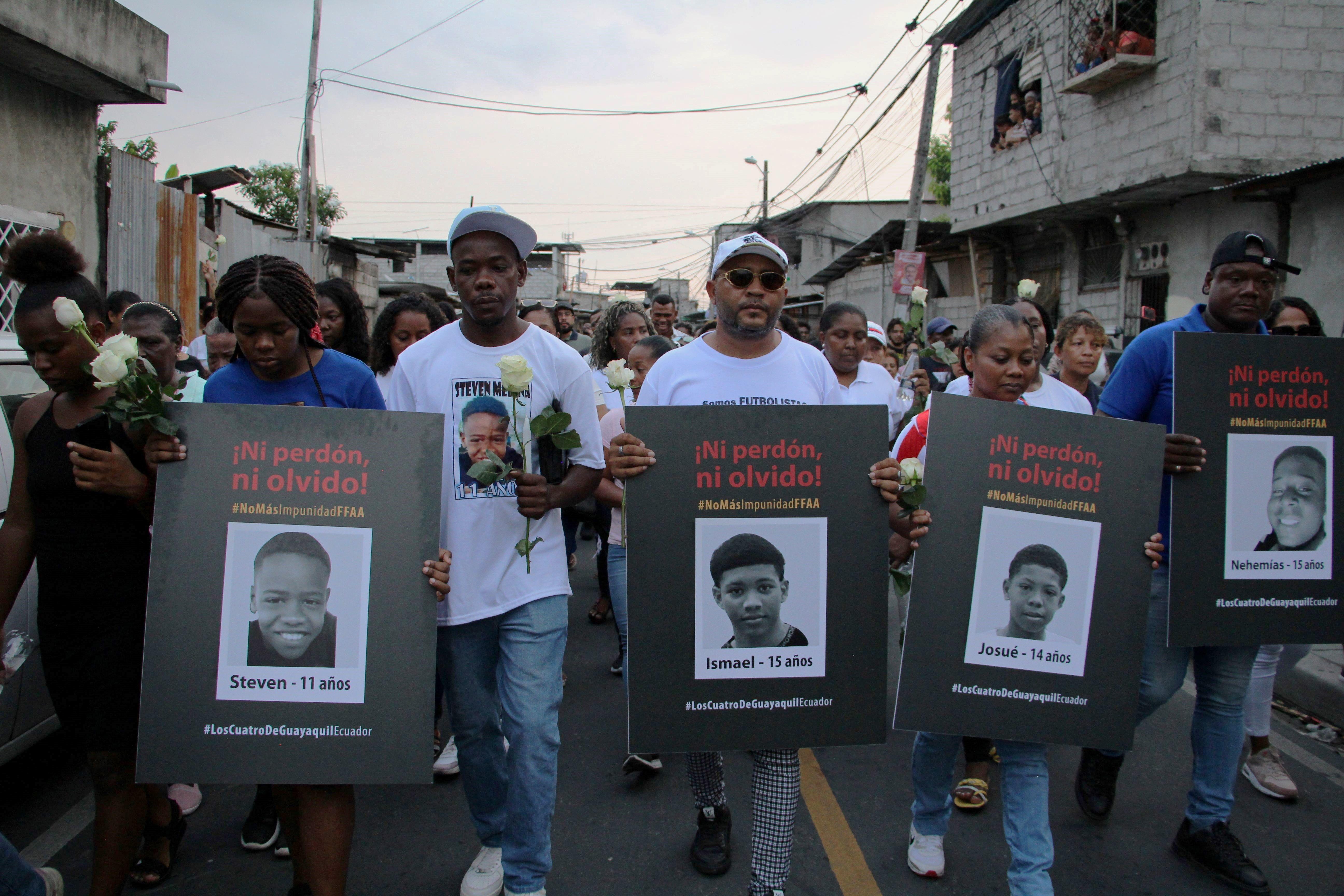 Personas que llevan carteles con las fotos de los cuatro de Guayaquil.