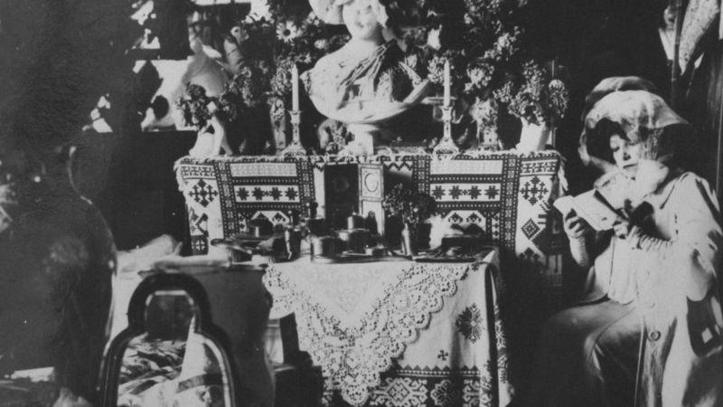 Sarah Bernhardt lendo livro sentando em frente a uma mesa