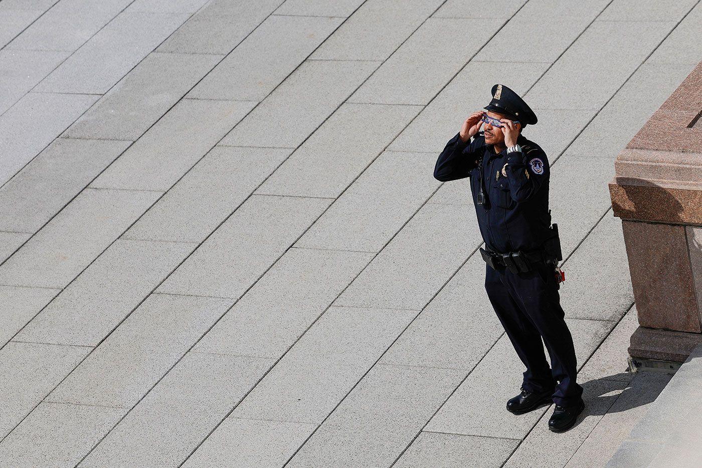 Militar uniformizado observando o eclipse com óculos de proteção 