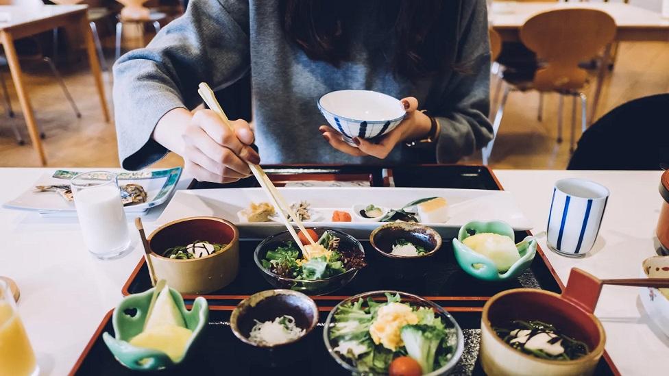 Pessoa comendo comida japonesa em restaurante
