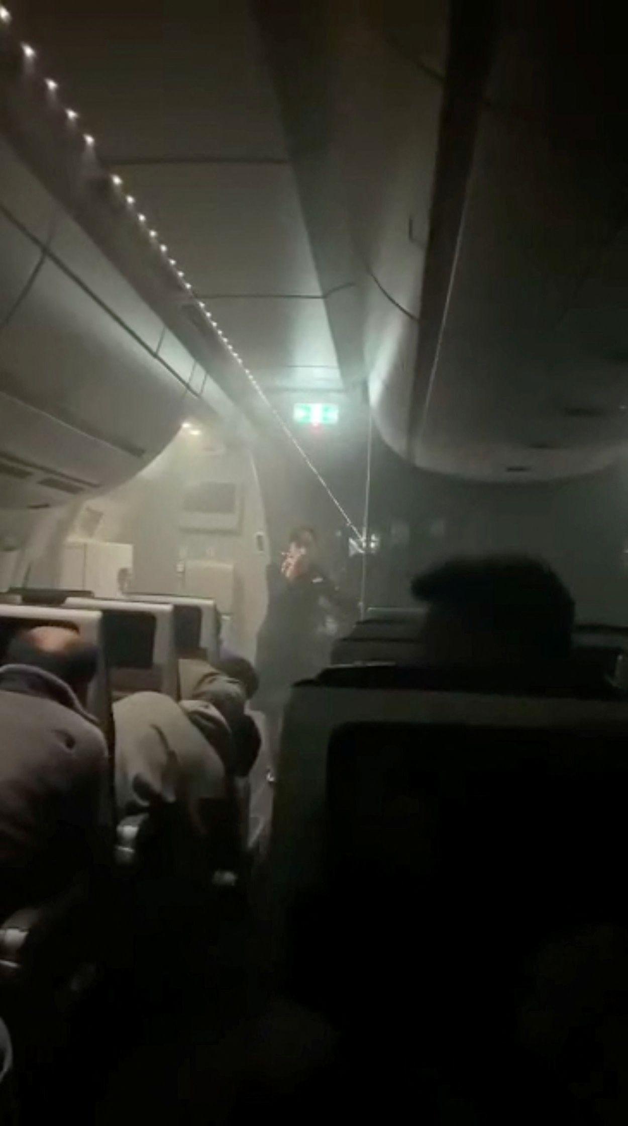 Pessoas sentadas em meio à fumaça dentro do avião A350 da Japan Airlines