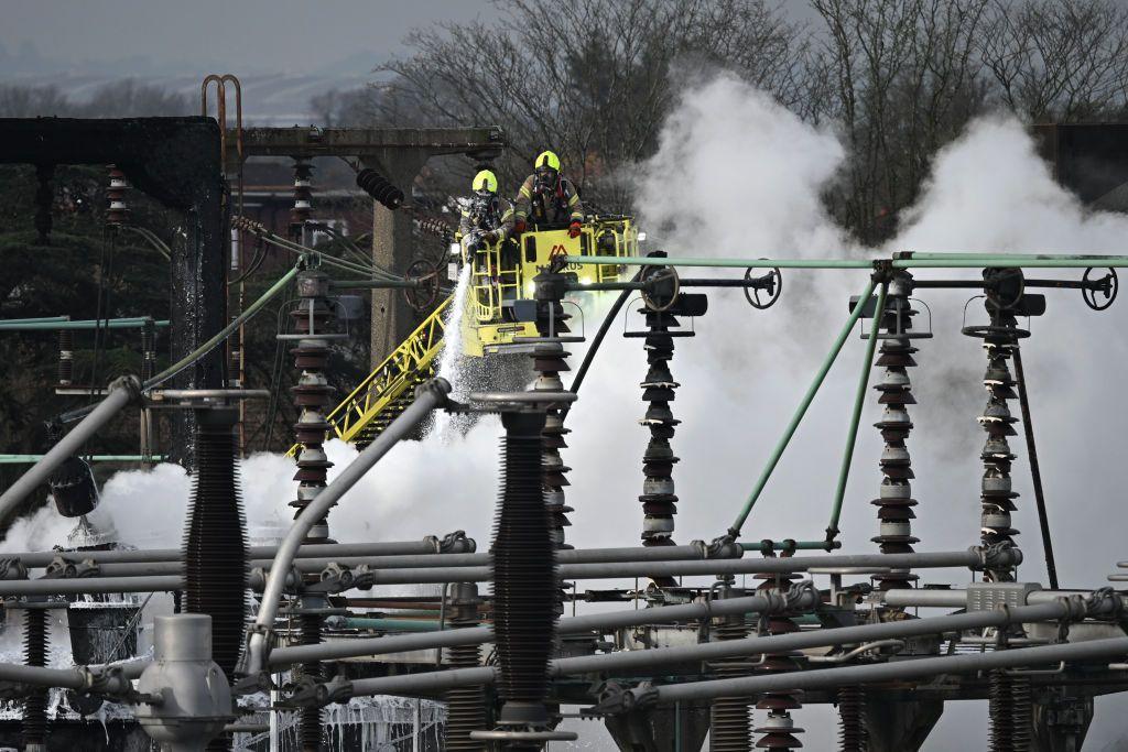 Bomberos subidos a grúas con mangueras en la mano extinguen los restos del fuego en la central eléctrica. 