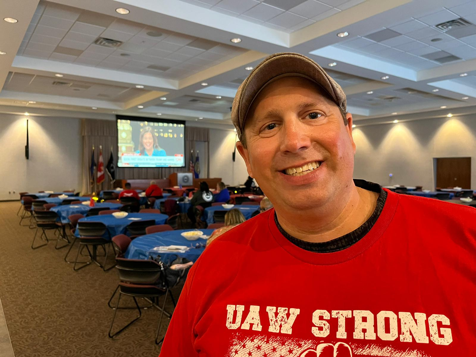 Joe Losier, de camisa vermelha com o nome do sindicato, em sala de reunião.