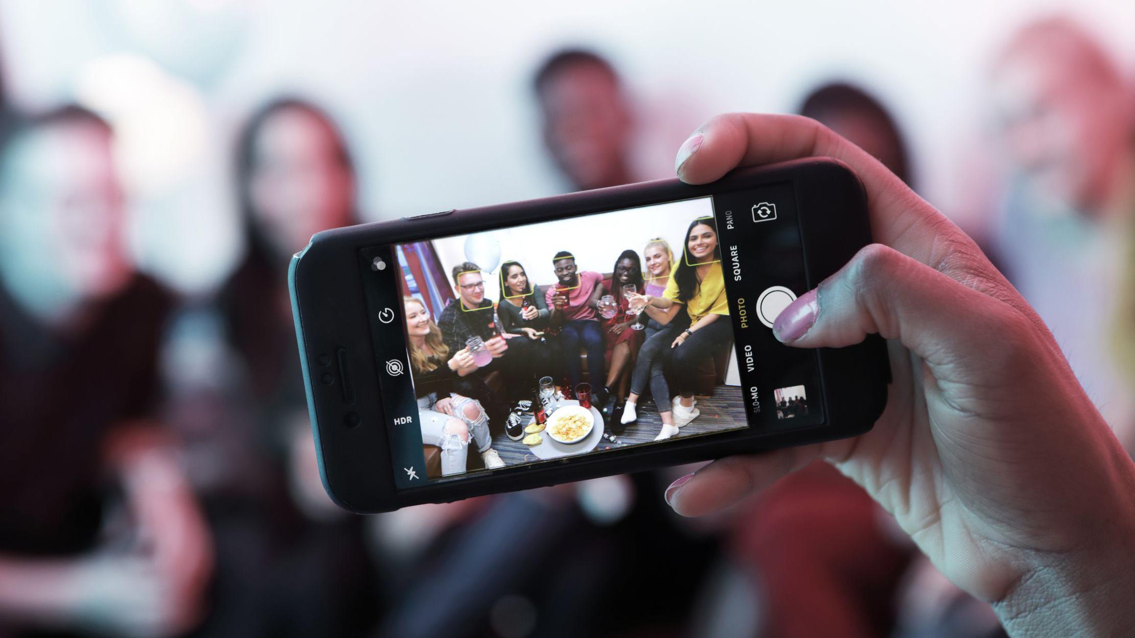 Un celular tomando una foto de jóvenes en una fiesta en una casa