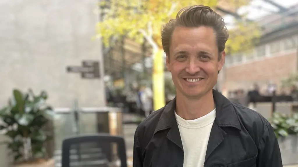 Fotografia mostra homem branco com jaqueta de couro sorrindo