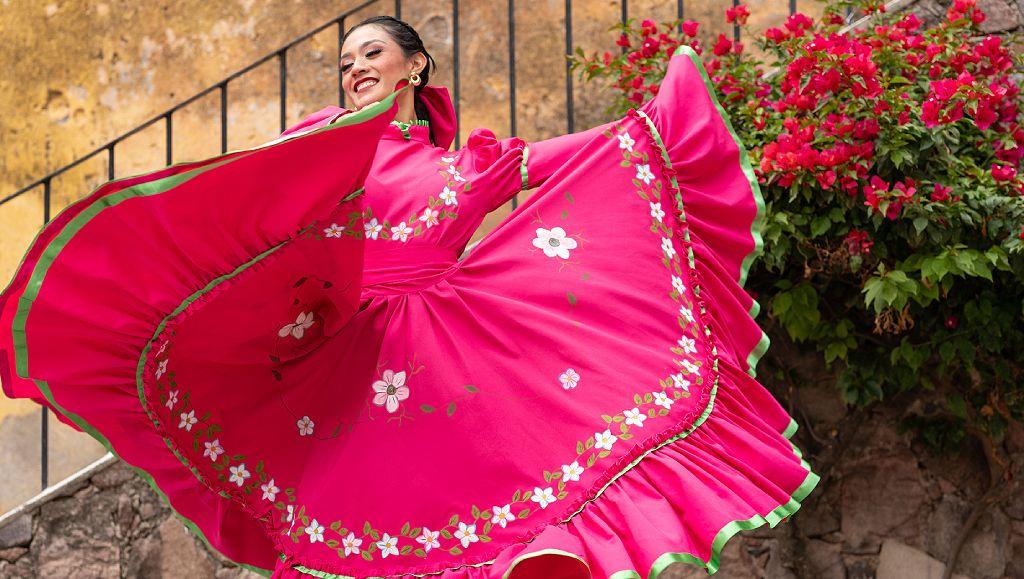 Bailarina con vestido rosa mexicana al lado de una vernanera