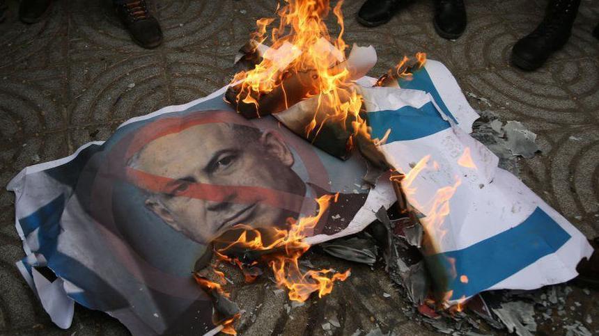 Bandera israelí en llamas con imagen de Netanyahu