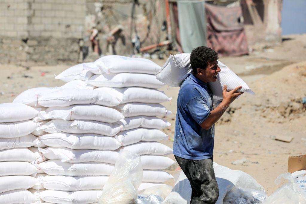 A Palestinian man carries a bag of flour provided as aid to families at the United Nations Relief and Works Agency for Palestine Refugees (UNRWA) distribution centre, in the Al-Shati refugee camp in Gaza city on 31 July 2023