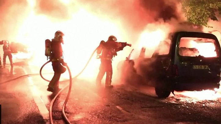 Carro pegando fogo enquanto bombeiro tenta apagar incêndio em Nanterre