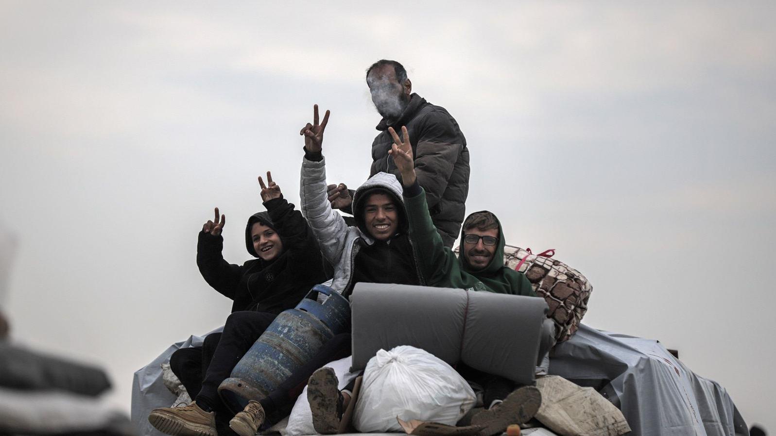 نازحون فلسطينيون يلوحون أثناء عبورهم ممر نتساريم باتجاه الشمال بعد انسحاب القوات الإسرائيلية من وسط غزة، يوم الاثنين، 10 فبراير، 2025.