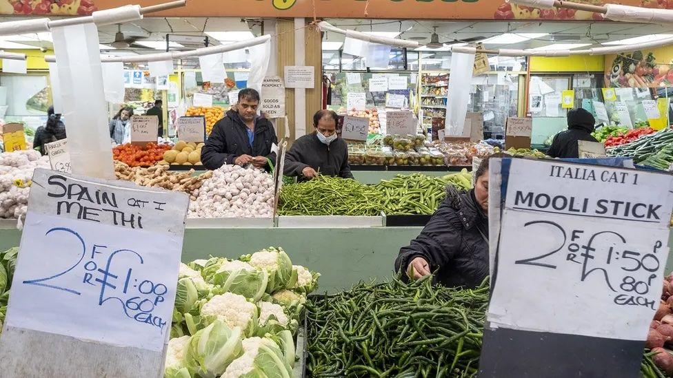 Diversas barracas de feira e placas com os preços dos produtos