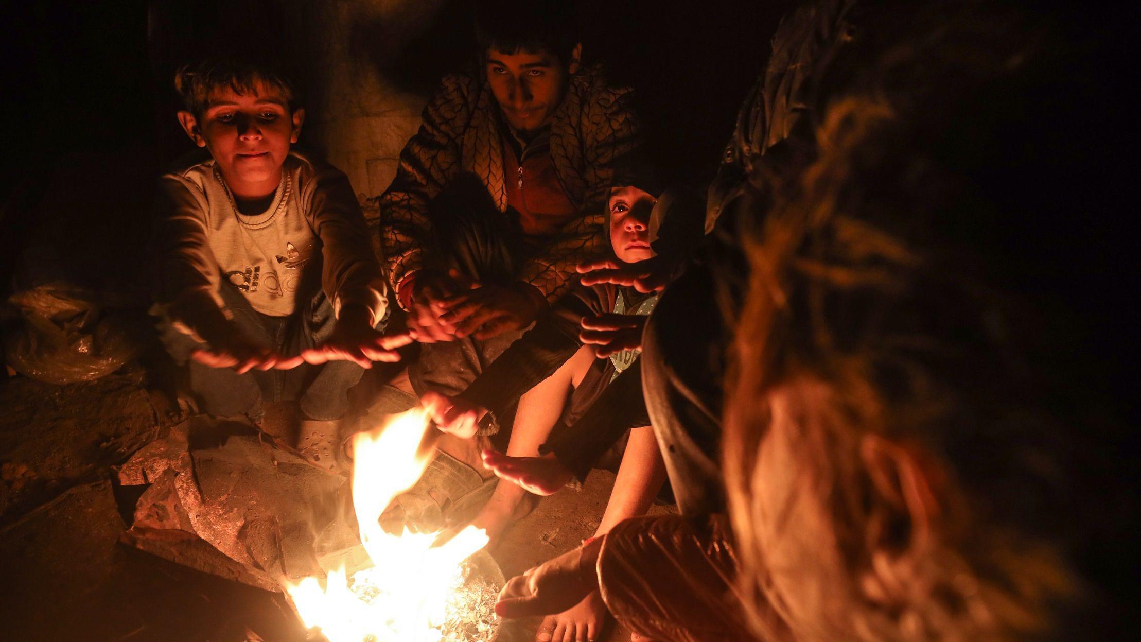 يتجمع النازحون الفلسطينيون حول النار للتدفئة في مخيم خلال الطقس البارد وسط الصراع بين إسرائيل وحماس في دير البلح، قطاع غزة، في 27 ديسمبر 2024.