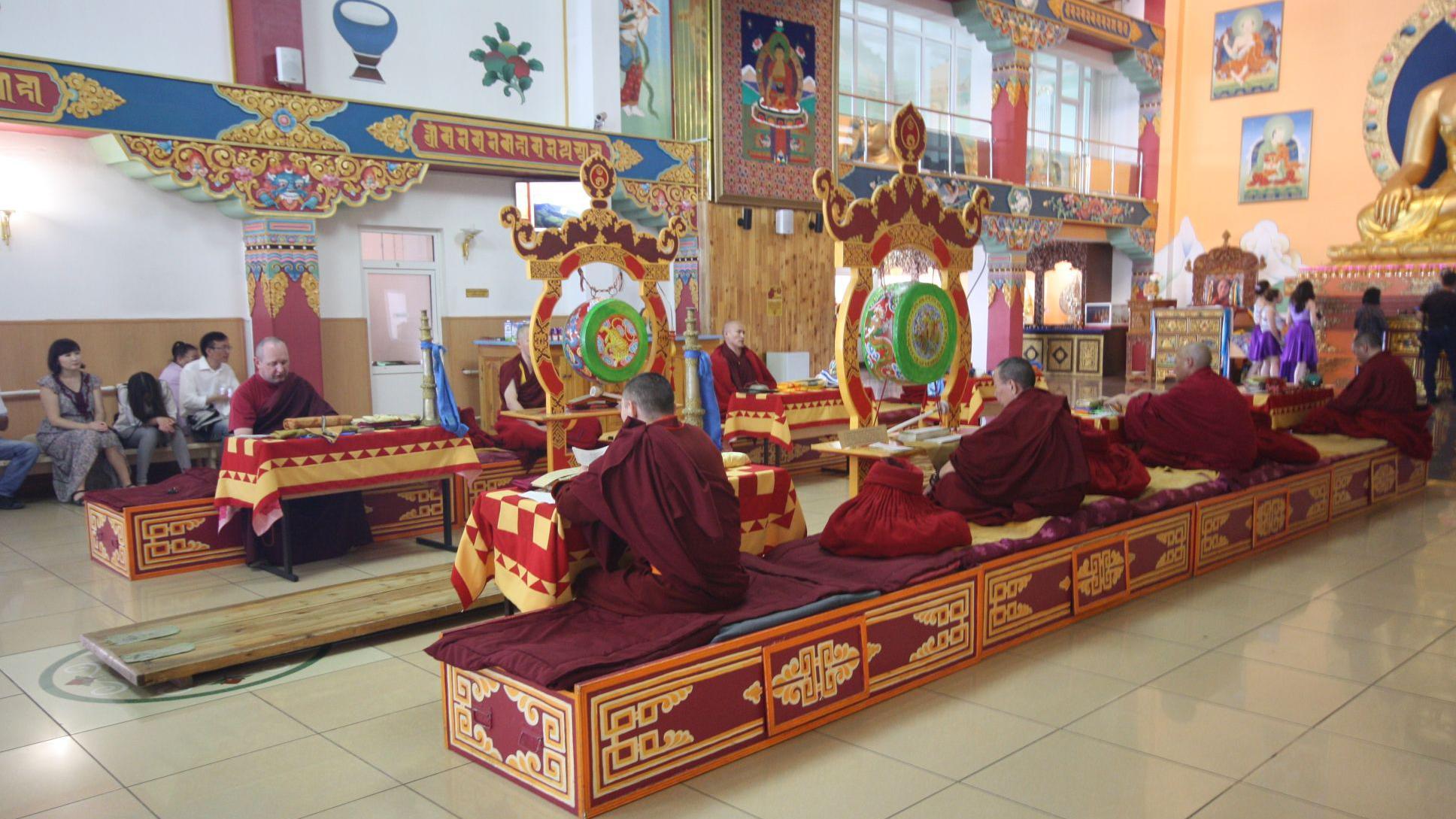 Monges sentados em bancos decorados dentro de um templo